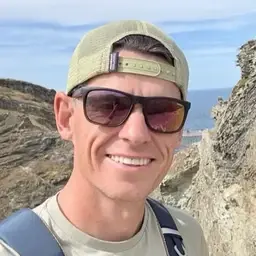 David O’Sullivan smiling on a coastal walk, in a cap and sunglasses